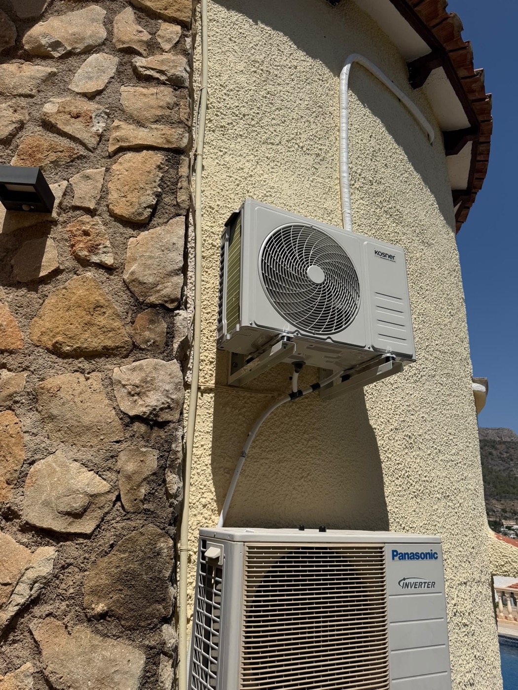 Unidades exteriores Kosner y Panasonic instaladas en una fachada de piedra